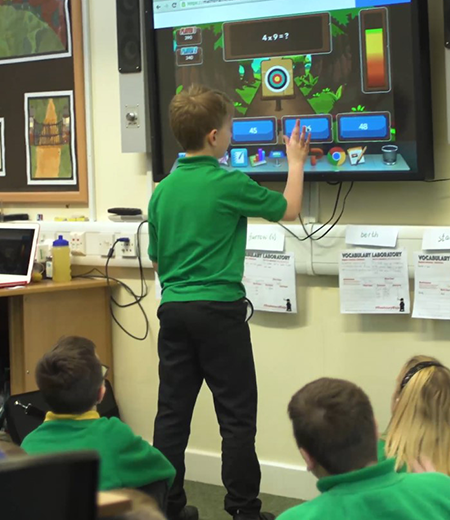 A young boy using an interactive screen in a classroom